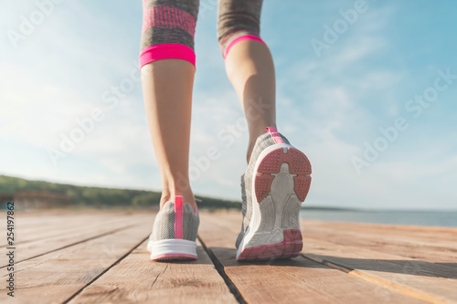 Legs in sneakers close-up. Health and Yoga Concept. Rear view close up strong athletic female legs and running shoes of sport. Sporty young girl practicing yoga. Woman do gymnastics outdoors
