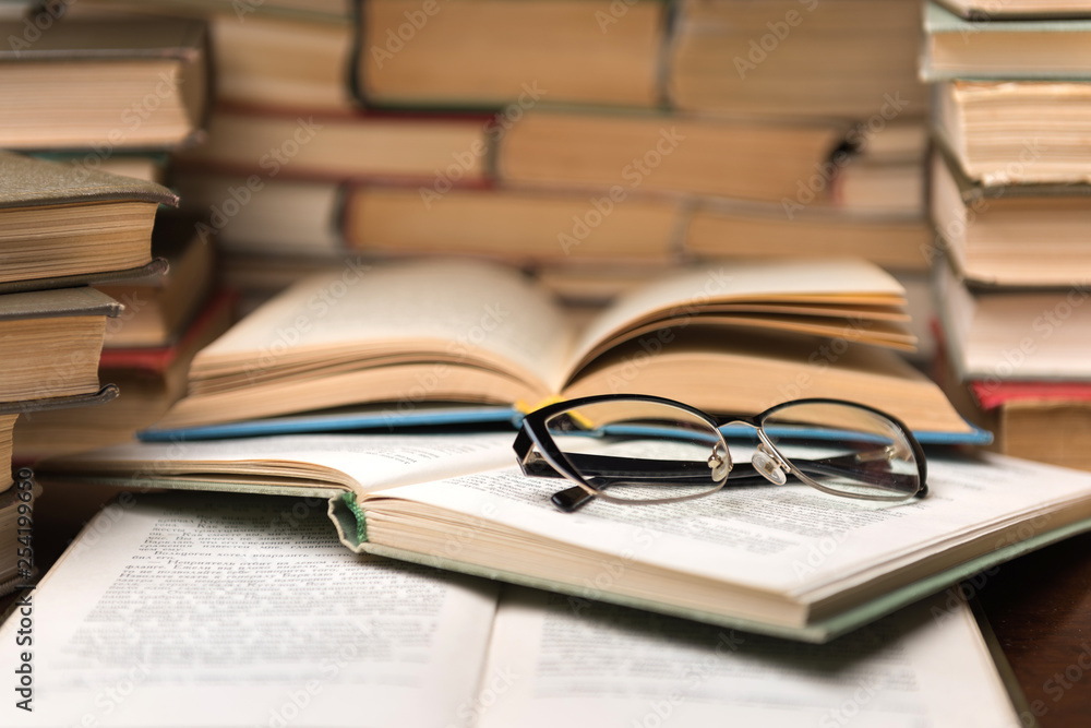 Open book and glasses on wood desk in the library room with blurred focus for education background and back to school concept Open book and glasses on wood desk in the library room with blurred focus for education background and back to school concept