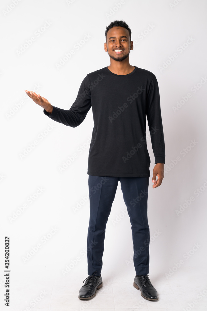 Full body shot of happy young handsome African man showing something Full body shot of happy young handsome African man showing something