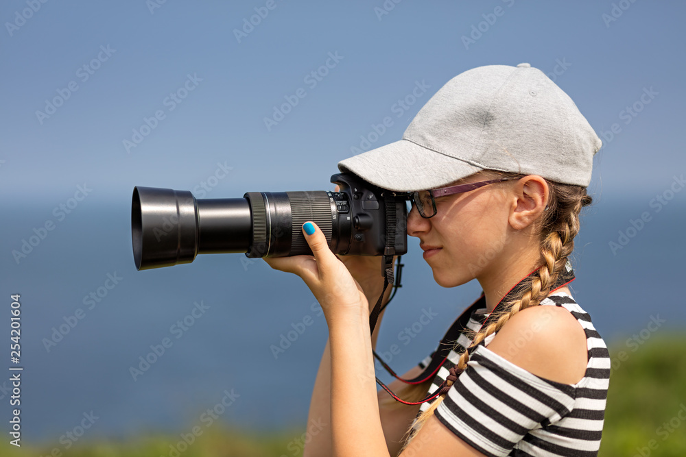 12 year old girl taking pictures with a long lens in a beautiful scenic of Irish cliffs