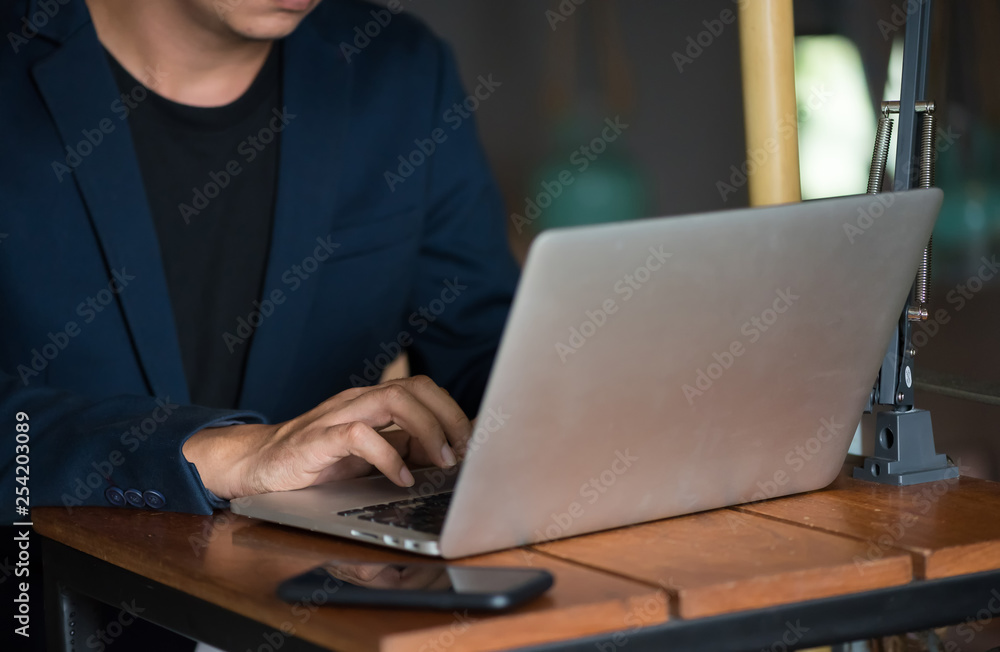 Close up Asian business man using laptop for working in coffee shop in selective focus.
