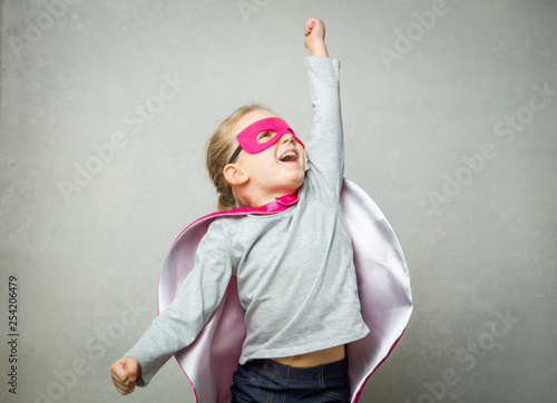 Little girl pretending that she is flying wearing a cloak and mask photo