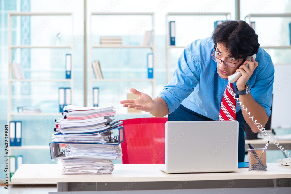 Handsome businessman unhappy with excessive work in the office Handsome businessman unhappy with excessive work in the office
