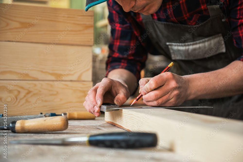 The worker makes measurements of a wooden board with ruler. The worker makes measurements of a wooden board with ruler.