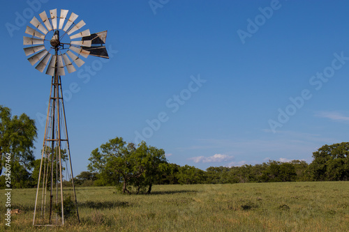 Windmill in pasture with blue sky