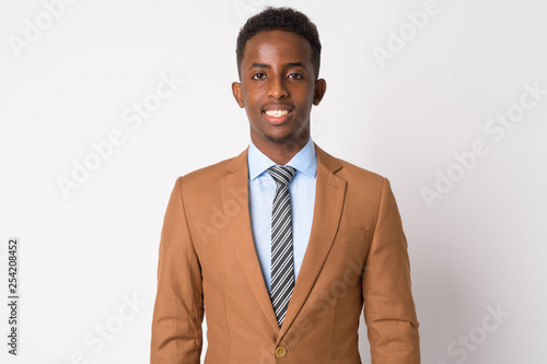 Portrait of young happy African businessman in brown suit smiling