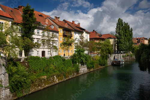 Historic houses on the ivy covered Hribar Quay embankment of the Ljubljanica river canal waterway in the old town of Ljubjlana Slovenia