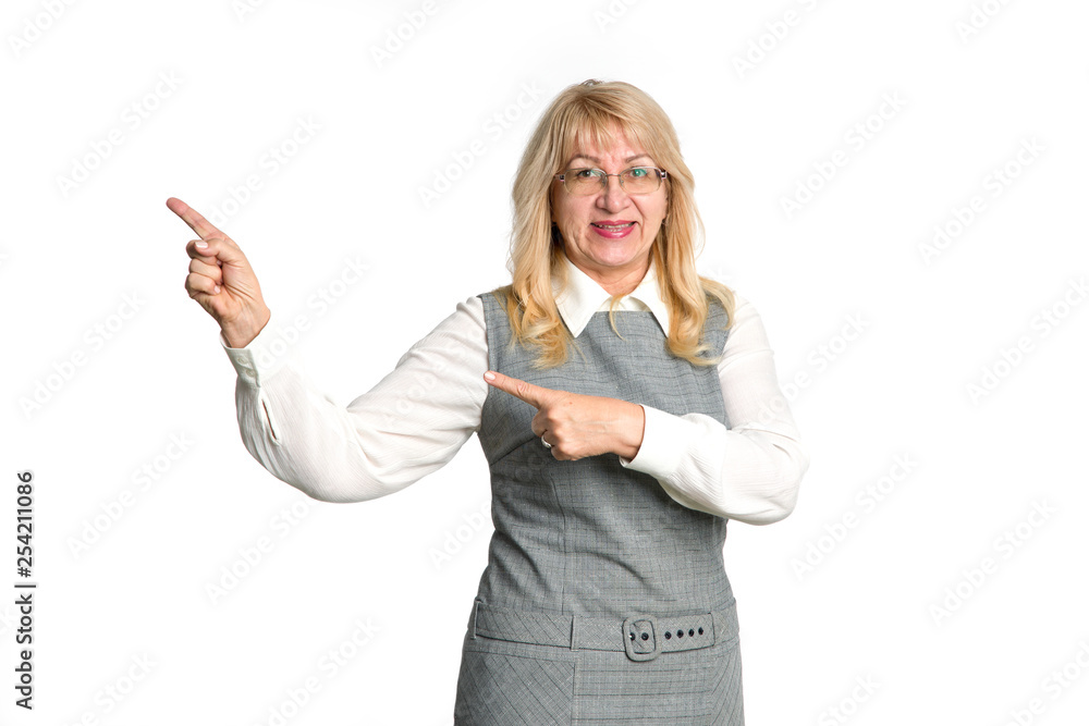 Mature woman shows finger to the left side isolated on white background. Senior woman pointing to empty space for text. Teacher.