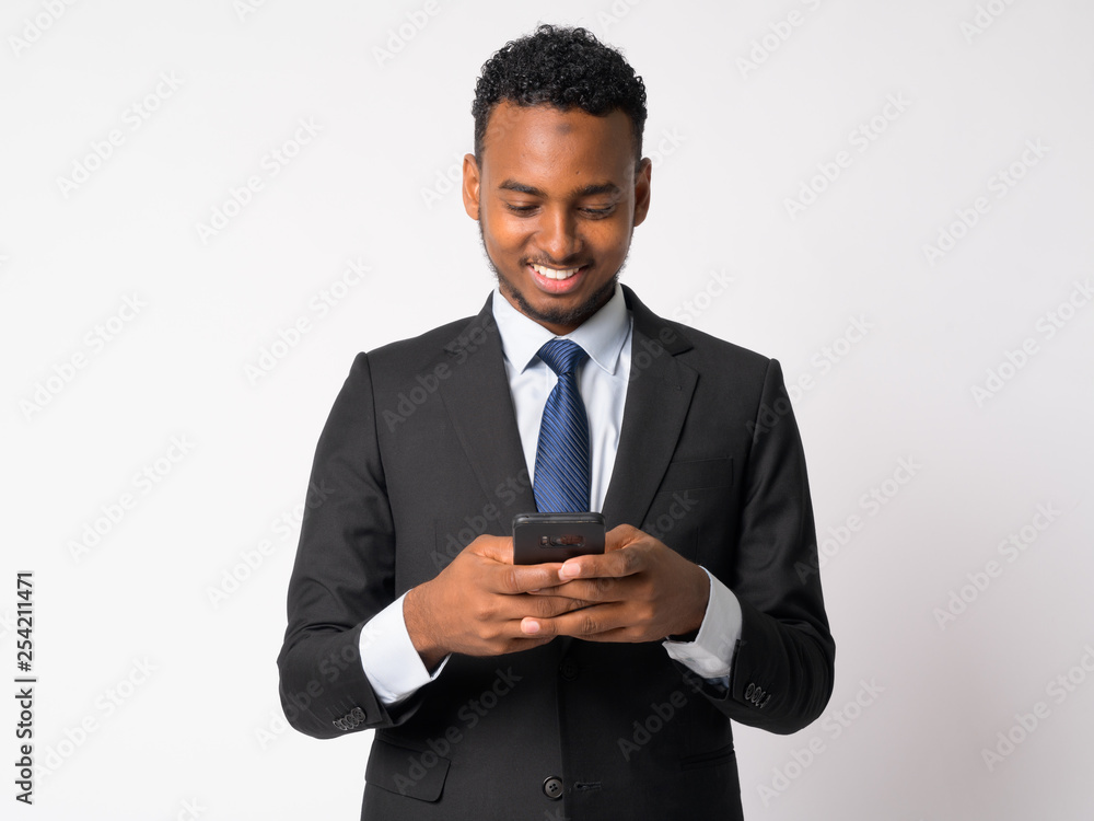 Happy young handsome African businessman using phone Happy young handsome African businessman using phone
