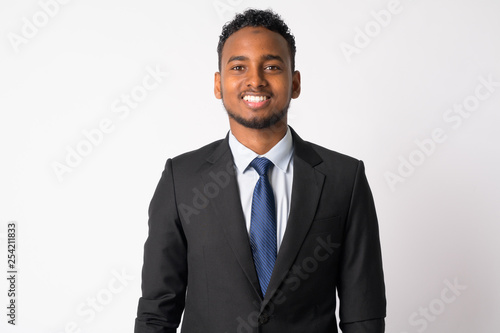 Happy young handsome African businessman in suit smiling