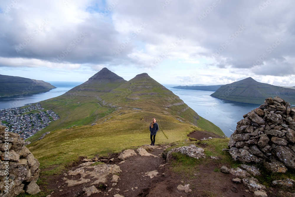 Young woman hiking near the town of Klaksvik, Bordoy, Faroe Islands