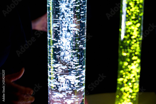therapy sensory stimulating multi sensory room, woman interacting with colored lights bubble tube lamp during therapy session