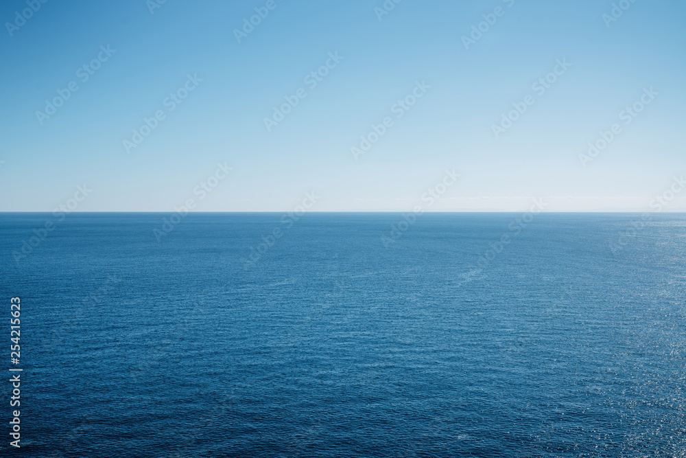 Clean blue sky above a blue surface of the sea.