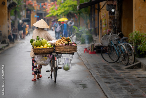 Woman walking in Hoi An with fruits