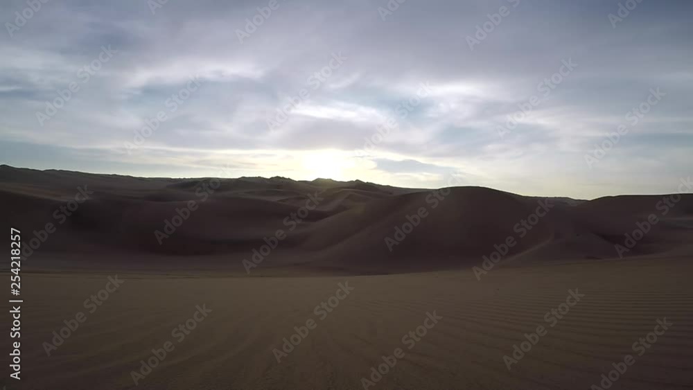 Beautiful sunset timelapse over the sand dunes of the desert near Huacachina, Peru. The sun appears out of the clouds and it's golden rays fill the desert with a golden glow until it finally descends. Beautiful sunset timelapse over the sand dunes of the desert near Huacachina, Peru. The sun appears out of the clouds and it's golden rays fill the desert with a golden glow until it finally descends.