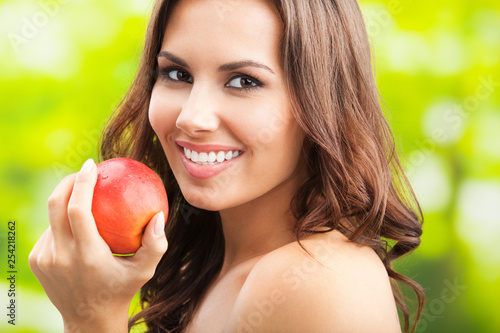 Young happy smiling woman with apple, outdoors