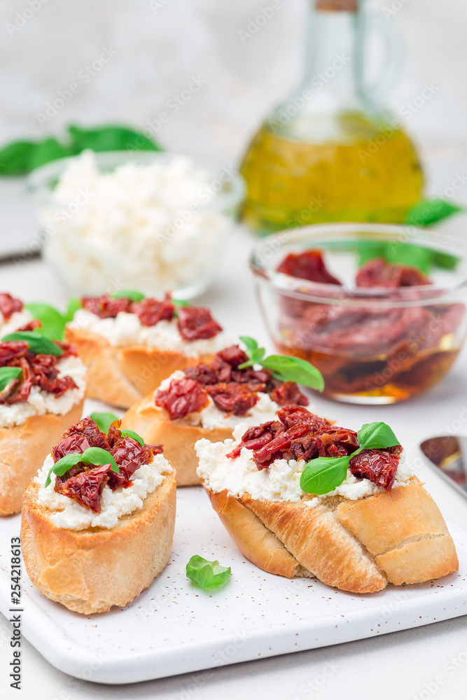 Bruschetta with sun dried tomato, feta and philadelphia cheese and basil on a ceramic plate, vertical