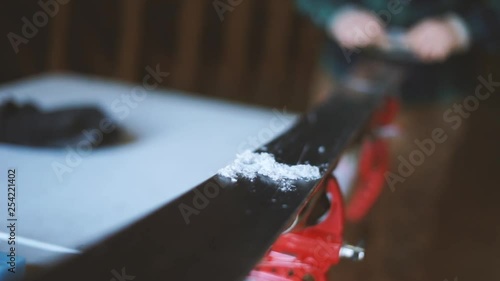 Person scrapes wax off of skis after ironing. photo