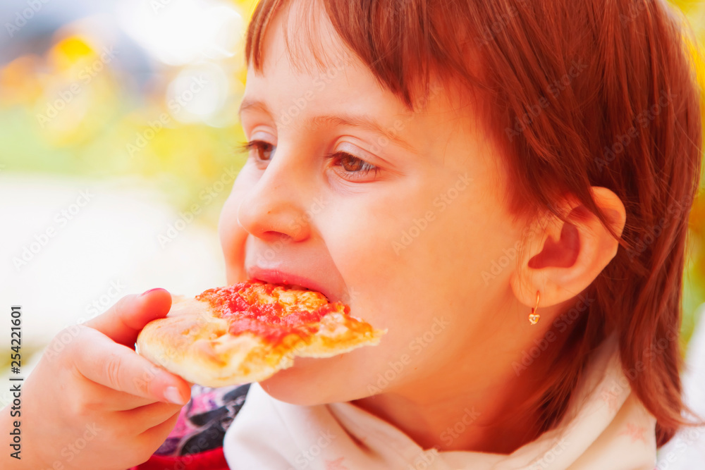 Beautiful little child girl enjoying a delicious pizza. Food, hunger, rest, holiday concept.