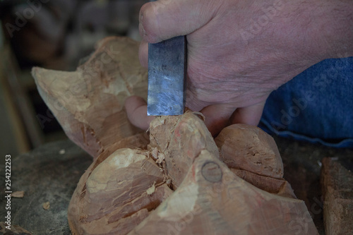 Holzschnitzerei, mit Stechbeitel arbeitende Hände an eine Holzmaske, Nahaufnahme  photo