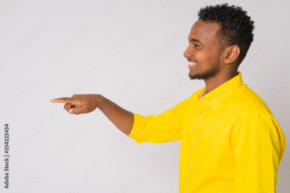Profile view of happy young African businessman pointing finger Profile view of happy young African businessman pointing finger