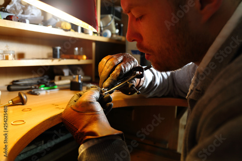 Jeweler measuring a ring with compass divider in a workshop lith with warm light photo