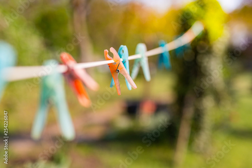 Pink plastic clothespin hanging on clothes hanger with nature background