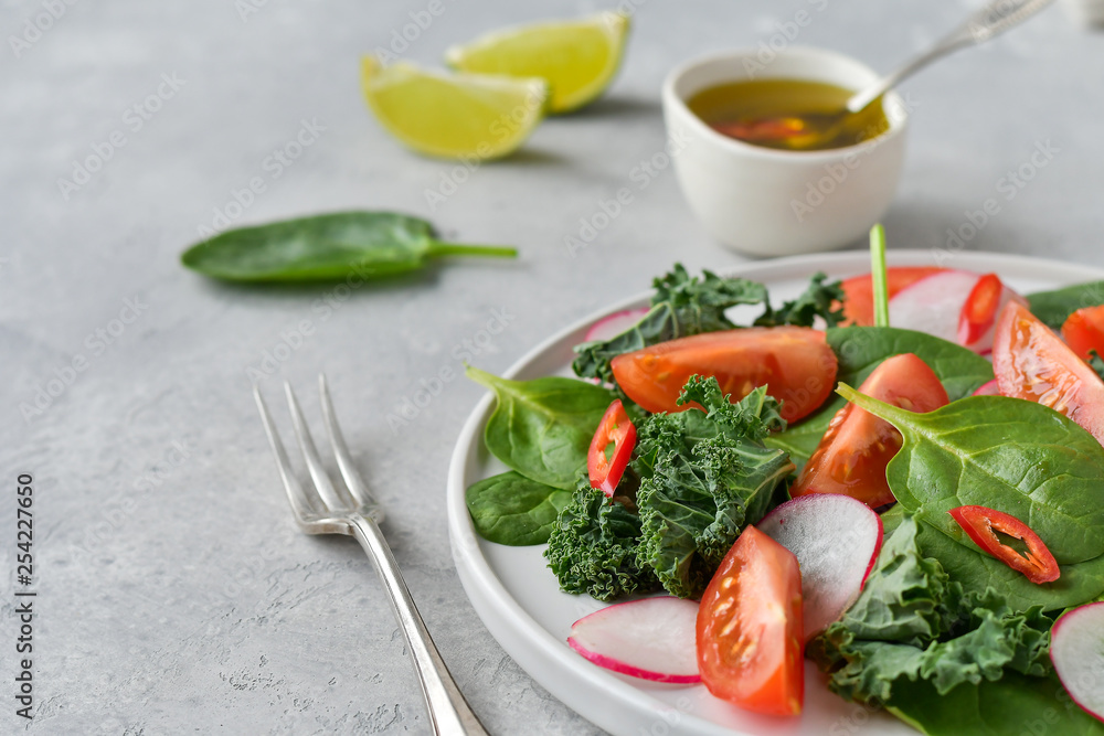 fresh salad of organic spinach, kale, red tomatoes and radish with olive oil and lime juice. healthy eating concept. diet, vegan cuisine. light background, selective focus fresh salad of organic spinach, kale, red tomatoes and radish with olive oil and lime juice. healthy eating concept. diet, vegan cuisine. light background, selective focus
