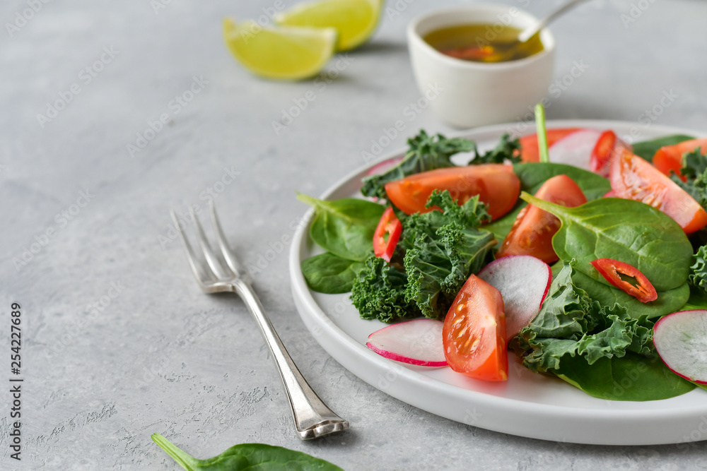 fresh salad of organic spinach, kale, red tomatoes and radish with olive oil and lime juice. healthy eating concept. diet, vegan cuisine. light background, selective focus fresh salad of organic spinach, kale, red tomatoes and radish with olive oil and lime juice. healthy eating concept. diet, vegan cuisine. light background, selective focus