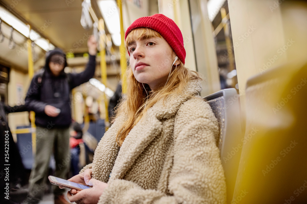 junge Frau, Mädchen, Teenager, sitzt mit ihrem Smartphone, Handy, in der U-Bahn junge Frau, Mädchen, Teenager, sitzt mit ihrem Smartphone, Handy, in der U-Bahn