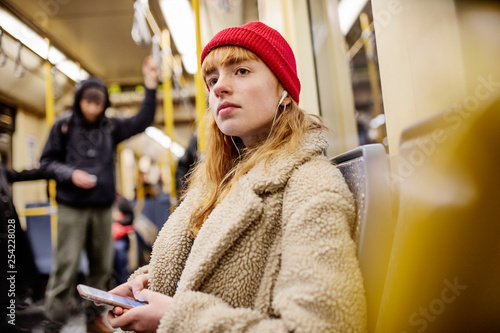 junge Frau, Mädchen, Teenager, sitzt mit ihrem Smartphone, Handy, in der U-Bahn photo