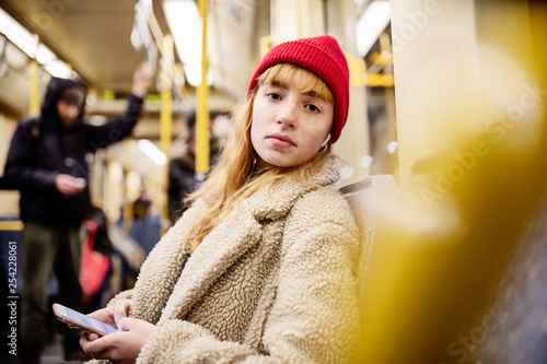 junge Frau, Mädchen, Teenager, sitzt mit ihrem Smartphone, Handy, in der U-Bahn photo