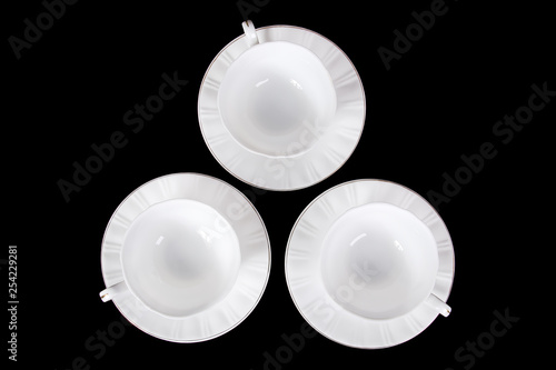 Three empty white tea cups stand on the table on a black background, top view