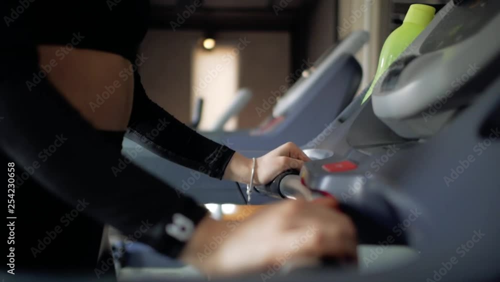 athletic cute young brunette girl goes in for sports on a treadmill. sports girl in black sportswear. view of the arms on the simulator athletic cute young brunette girl goes in for sports on a treadmill. sports girl in black sportswear. view of the arms on the simulator