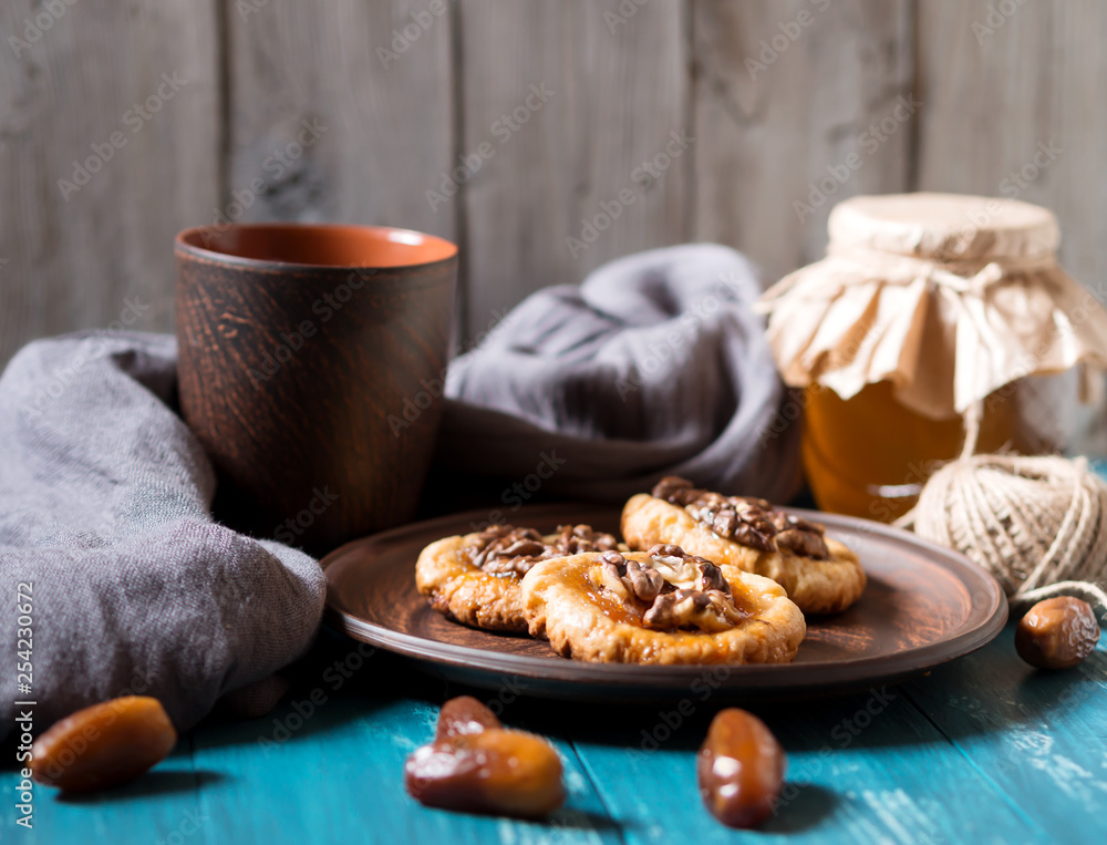 Romantic morning still life, in a rustic style with cookies, a glass jar of honey and scattered dates on a turquoise wooden background Romantic morning still life, in a rustic style with cookies, a glass jar of honey and scattered dates on a turquoise wooden background