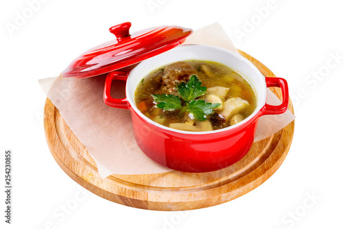Red pot of soup with beef and mushrooms served at a wooden tray isolated at white background.