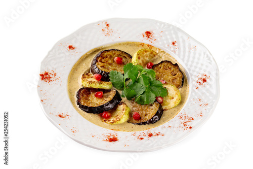 Plate of grilled eggplant and squash slices served with sauce isolated at white background.