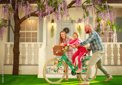 Happy parents with a child, daughter, learn to ride a bike, family lifestyle summer vacations at home