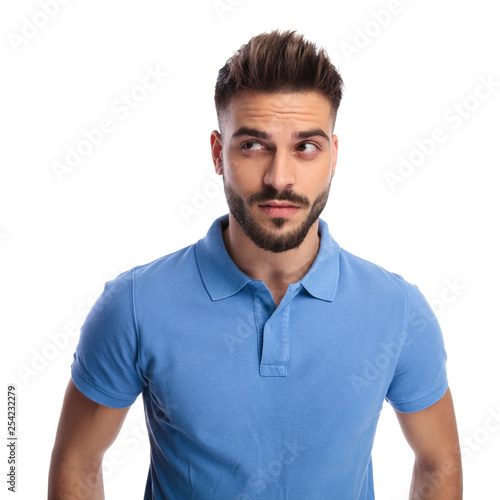 Thoughtful young man wearing a light blue polo looking upwards at a side © Viorel Sima