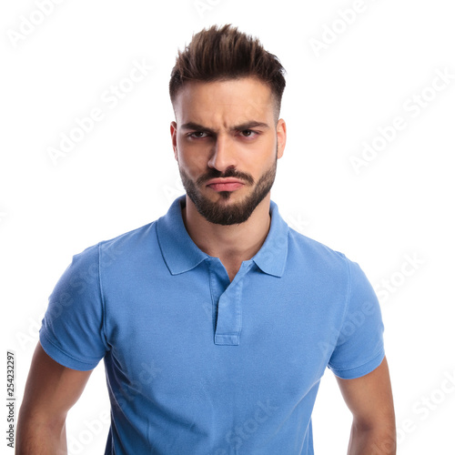 Young imature man wearing a light blue polo frowning photo