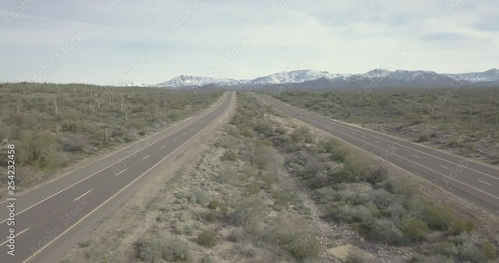 Aerial view of a highway through the desert heading into snow covered mountains. Aerial view of a highway through the desert heading into snow covered mountains.
