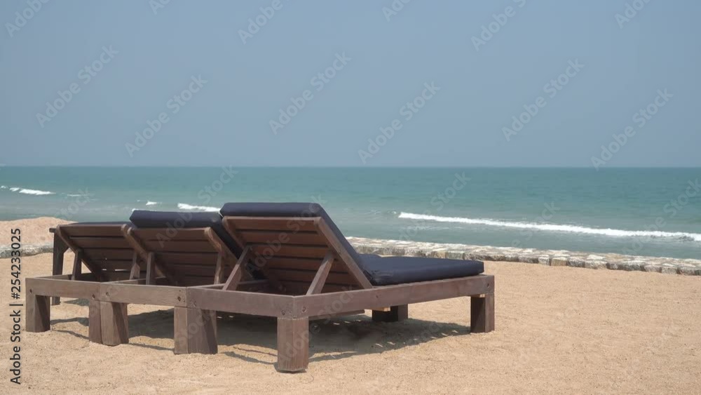 Three empty chaise lounge chair face the waves on a deserted sandy beach. Concept: lifestyle, tourism, relaxation, resort life, romantic, isolated Three empty chaise lounge chair face the waves on a deserted sandy beach. Concept: lifestyle, tourism, relaxation, resort life, romantic, isolated