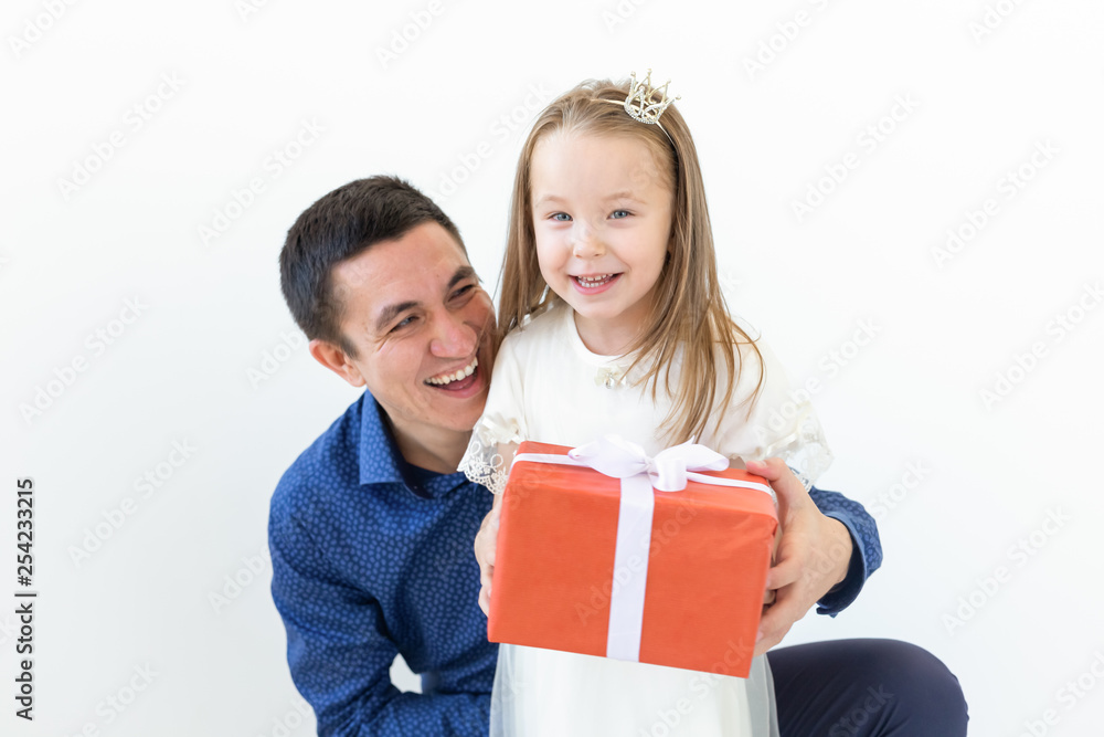 Fathers day, fatherhood and family concept - Father embrace his daughter holding red gift box over white background Fathers day, fatherhood and family concept - Father embrace his daughter holding red gift box over white background