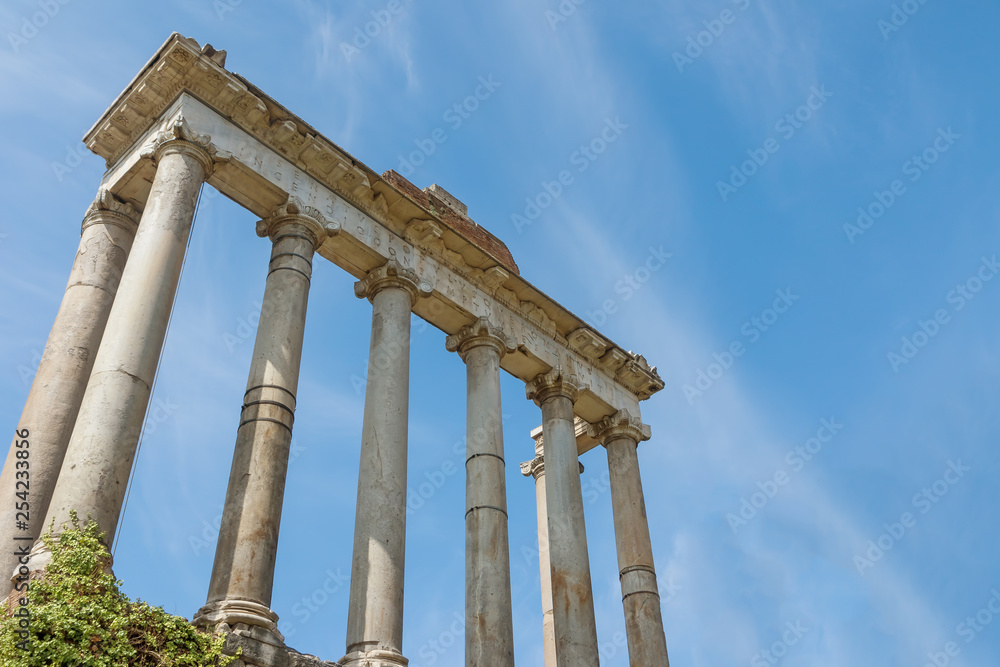 Pillars and ruins of the ancient Saturn Temple in Forum Romanum. Rome. Italy. Free place for your text is in the blue sky is in the background.