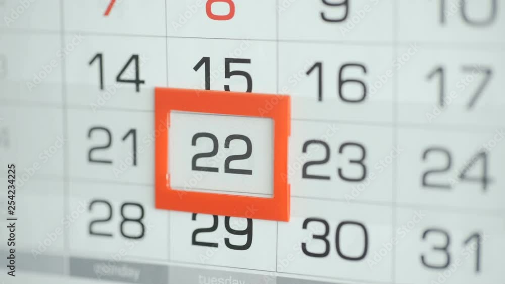Woman's hand in office changes date at wall calendar. Changes 21 to 22 Woman's hand in office changes date at wall calendar. Changes 21 to 22