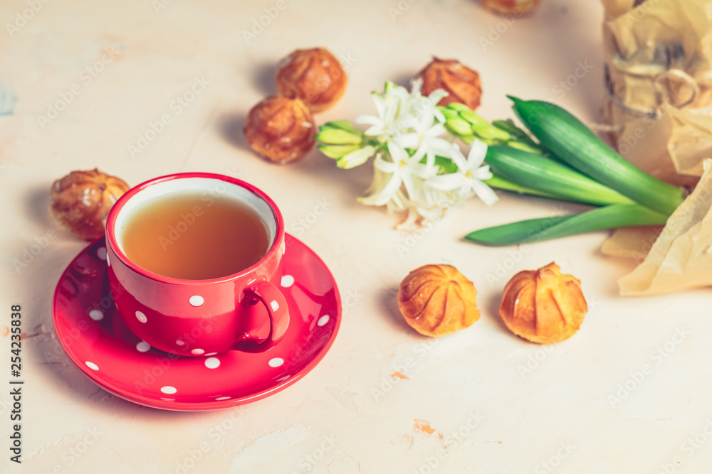 Red in white dotted cup of tea, profiteroles and hyacinths Red in white dotted cup of tea, profiteroles and hyacinths