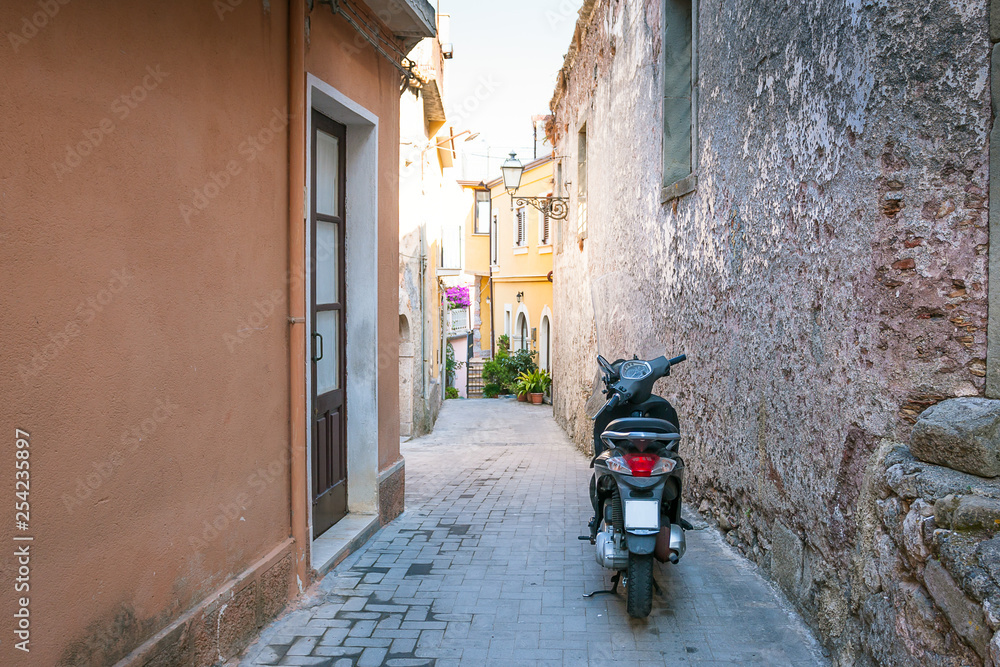 Motobike scooter parked in a typical narrow old street in Sicile, Italy