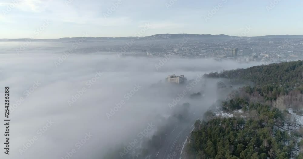 4K aerial video with forward motion and a high angle view of the beautiful hills of Ekeberg in Oslo the skyline covered in thick fog at daytime. 4K aerial video with forward motion and a high angle view of the beautiful hills of Ekeberg in Oslo the skyline covered in thick fog at daytime.