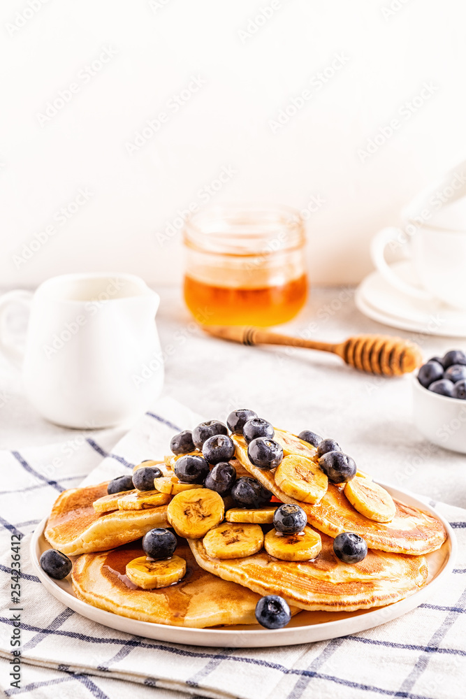 Pancakes with banana,  blueberries on white plate.