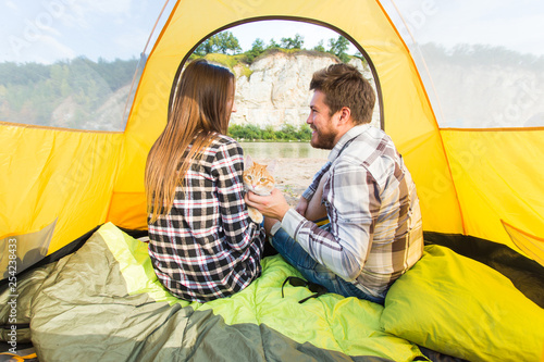 people, summer tourism and nature concept - young couple resting in camping tent, view from inside © satura_